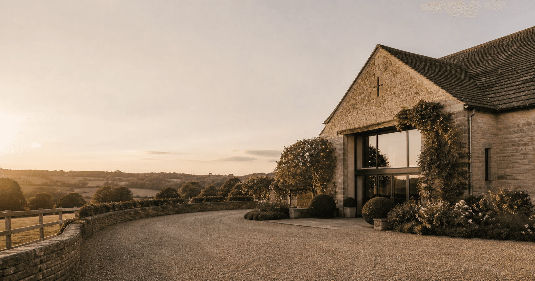 An English country house wedding venue photographed at golden hour with long shadows, shot in an editorial magazine style with warm, understated tones.